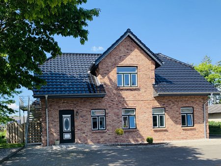 Ferienwohnungen Thomsen: Frontansicht Haus - roter Stein, schwarzes Dach, grün-weiße Fenster